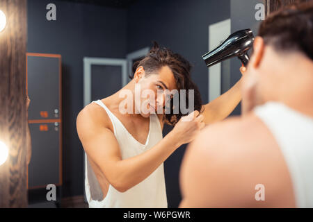Attraente bella giovane uomo di toccare i suoi capelli Foto Stock