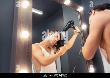 Piacevole uomo bello la sua asciugatura capelli lunghi Foto Stock