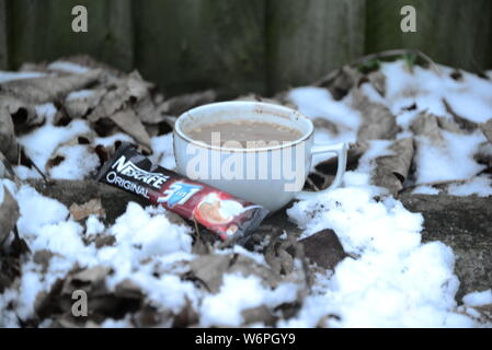 Tazza di Nescafe in inverno la refrigerazione con neve tazza di caffè e una fetta di torta tempo di interruzione in condizioni di clima freddo di bere il caffè esce intorno a Snowy White snow Nescafe Foto Stock