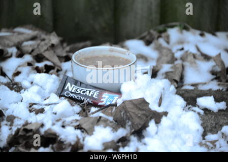 Tazza di Nescafe in inverno la refrigerazione con neve tazza di caffè e una fetta di torta tempo di interruzione in condizioni di clima freddo di bere il caffè esce intorno a Snowy White snow Nescafe Foto Stock