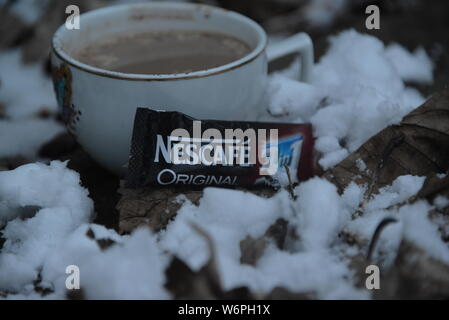 Tazza di Nescafe in inverno la refrigerazione con neve tazza di caffè e una fetta di torta tempo di interruzione in condizioni di clima freddo di bere il caffè esce intorno a Snowy White snow Nescafe Foto Stock