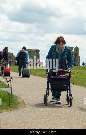 Persone basandosi su ruote / trasporto su ruote utilizzando il percorso pedonale per raggiungere o partono / lascia Stonehenge antico monumento. Amesbury. Regno Unito (110) Foto Stock