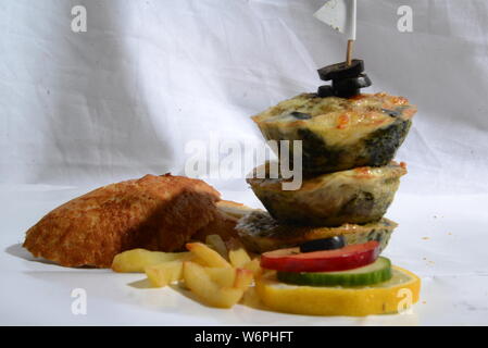 Cesto pieno di cibi che serve cibo con patatine fritte olive vegetariani vegan cetriolo calce fast food e alimenti insalubri cibi spazzatura bellezza del pane Foto Stock