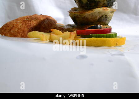 Cesto pieno di cibi che serve cibo con patatine fritte olive vegetariani vegan cetriolo calce fast food e alimenti insalubri cibi spazzatura bellezza del pane Foto Stock