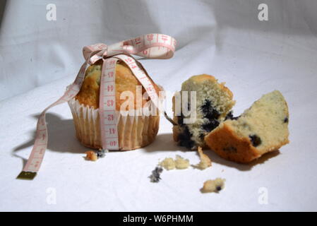 Cup cake e torte e perdere peso biscotto sta grasso e simbolo di dimensionamento del misuratore di peso la torta dal vicino foto significative junk food Foto Stock