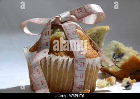 Cup cake e torte e perdere peso biscotto sta grasso e simbolo di dimensionamento del misuratore di peso la torta dal vicino foto significative junk food Foto Stock