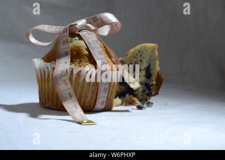 Cup cake e torte e perdere peso biscotto sta grasso e simbolo di dimensionamento del misuratore di peso la torta dal vicino foto significative junk food Foto Stock