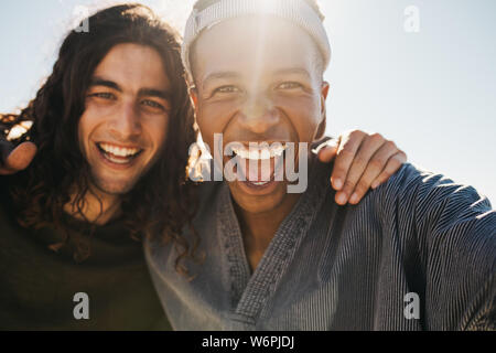 Eccitate due giovani uomini facendo una selfie fuori in una giornata di sole. Felice giovani amici facendo una selfie all'esterno. Foto Stock