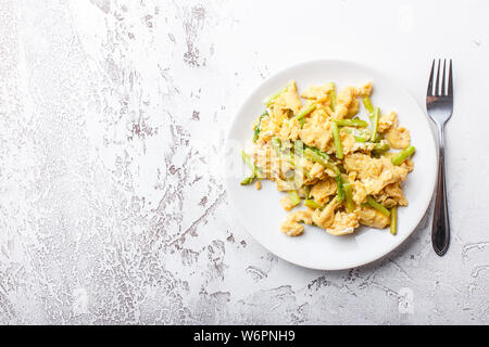 Uova strapazzate con freschi Asparagi verdi in una piastra bianca. La proteina sana prima colazione. Vista dall'alto. Spazio per il testo. Foto Stock