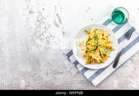 Uova strapazzate con freschi Asparagi verdi in una piastra bianca. La proteina sana prima colazione. Vista dall'alto. Spazio per il testo. Foto Stock