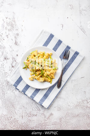 Uova strapazzate con freschi Asparagi verdi in una piastra bianca. La proteina sana prima colazione. Vista dall'alto. Spazio per il testo. Foto Stock