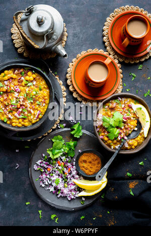 Indian vegan curry di lenticchie servita con un trito di cipolla, peperoncini verdi, il coriandolo fresco , le spezie e appena sfornati chai. Foto Stock