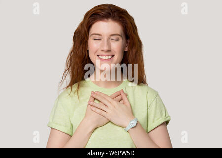 Chiusura femmina i suoi occhi tiene le mani sul petto si sente gratitudine Foto Stock