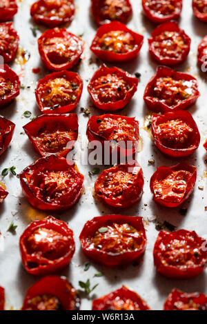 Arrosto di pomodori ciliegini, cosparsi di foglie di timo, sale marino e pepe nero pestato. Foto Stock