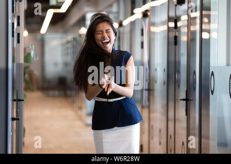 Funny happy asian imprenditrice vincitore sento contentissimo in piedi in ufficio Foto Stock