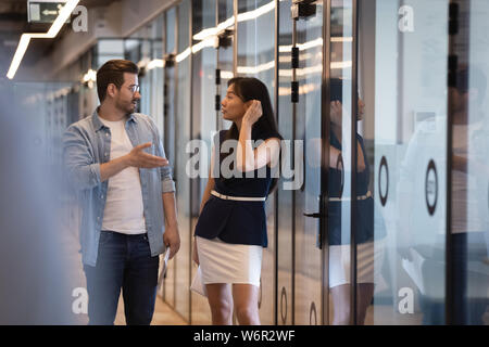 Due diversi collaboratori professionali parlando a piedi nel corridoio di office Foto Stock