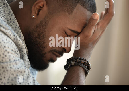 Sconvolto ha sottolineato giovane americano africano di coping di uomo con un forte mal di testa Foto Stock