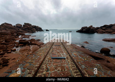 Francia, Bretagna Cotes d'Armor, rotaie che portano al mare in granito rosa di costa presso gli uomini Ruz faro di Ploumanach Foto Stock