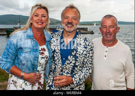 Ahakista, West Cork, Irlanda. 2 agosto, 2019. Come parte dell'Ahakista Festival di agosto Graham Norton ospita ogni anno il Graham Norton Tabella Quiz. Ospiti speciali, l'Irlanda e il Munster giocatori di rugby Fineen e Josh Wycherley ha partecipato anche alla festa. Graham è raffigurato con Martin e Deidre O'Sullivan, sughero. I proventi del quiz sono in corso per la Comunità Ahakista Associazione. Credito: Andy Gibson/Alamy Live News. Foto Stock