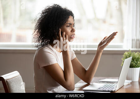 Razza mista donna avente conversazione difficile da telefono cellulare Foto Stock