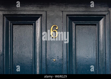 Numero civico 6 con le sei in bronzo su un lucido verniciato nero in legno porta anteriore Foto Stock