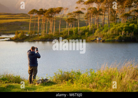 Tourist ammirando la vista di dodici l'Isola dei Pini, in piedi su un meraviglioso sfondo formato dalle vette aguzze di una catena montuosa denominata dodici perni o Foto Stock