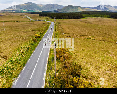 Ciclisti professionisti in competizione in Connemara regione in Irlanda. New Scenic 5 posti di campagna irlandese il paesaggio con le magnifiche montagne all'orizzonte, County G Foto Stock