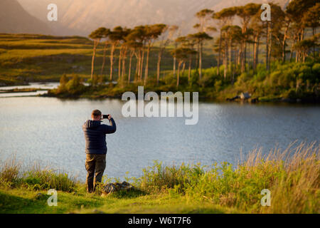 Tourist ammirando la vista di dodici l'Isola dei Pini, in piedi su un meraviglioso sfondo formato dalle vette aguzze di una catena montuosa denominata dodici perni o Foto Stock