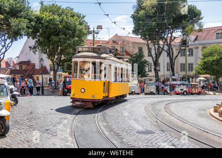 Il famoso tram giallo 28 passando davanti al duomo di Santa Maria a Lisbona, Portogallo Foto Stock