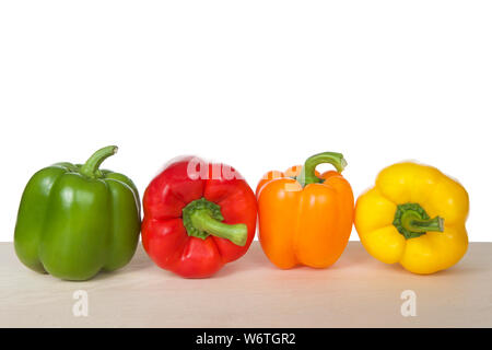 I peperoni su una tavola di legno isolato su bianco. Verde, rosso, arancione e giallo varietà. Come il pomodoro, peperoni sono frutti botanici ma culina Foto Stock