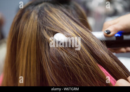 Parrucchiere utilizzando capelli su i capelli castani donna Foto Stock