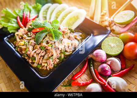 Piccante di carne macinata di maiale insalata Thai cibo servito a tavola con le erbe e le spezie ingredienti / Tradizione nordest Isaan cibo delizioso su piastra con qualche verdura fresca Foto Stock