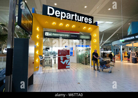 I viaggiatori spingendo un carrello bagagli davanti al gate di partenza all'aeroporto di Brisbane International Terminal, Queensland, QLD, Australia Foto Stock