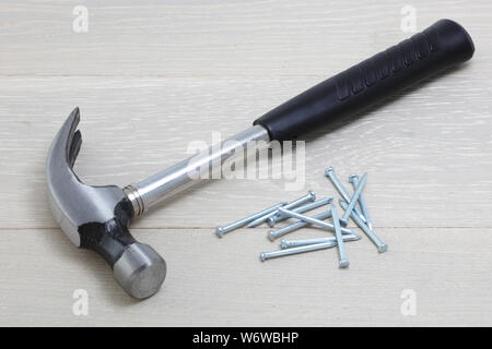 Un martello e chiodi su una superficie di legno Foto Stock