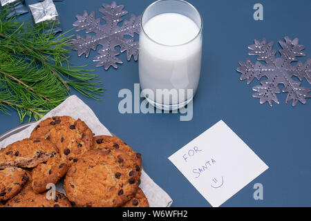 Latte e biscotti al cioccolato e una nota di Babbo Natale Foto Stock