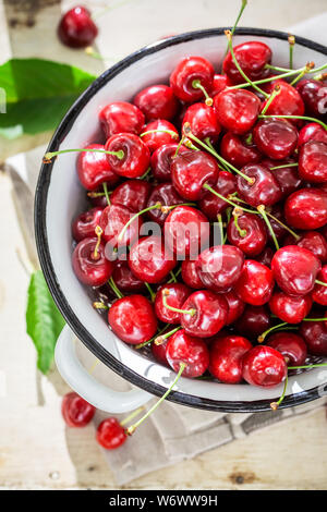 Fresche e gustose ciliegie dolci sul bianco vecchia succhieruola Foto Stock