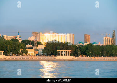 Vista della città di Khabarovsk dal fiume Amur. Il paesaggio urbano di sera al tramonto Foto Stock