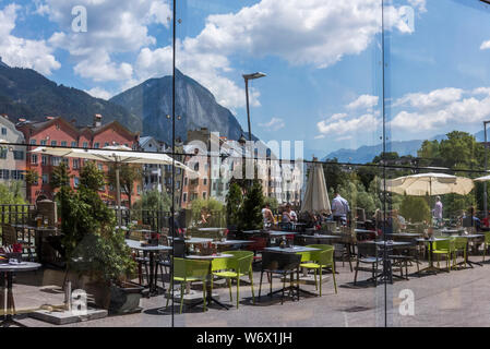 Finestra riflessioni di gente che si diverte durante una soleggiata giornata estiva nella città di Innsbruck campidoglio provinciale città del Tirolo in Austria Foto Stock