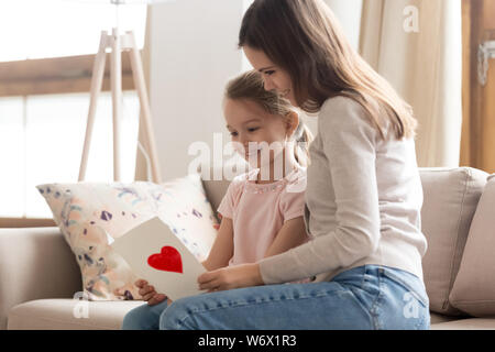 Madre e figlia seduta sul lettino la lettura di auguri in cartolina Foto Stock