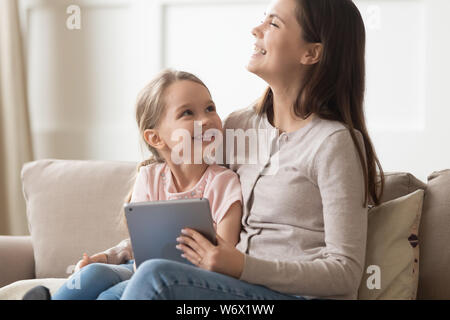 Ridendo madre e figlia piccola guardando cartoni animati su tablet Foto Stock