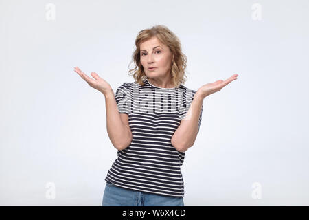 Vestito femminile casualmente in confusione, alza le spalle spalle come non so rispondere Foto Stock