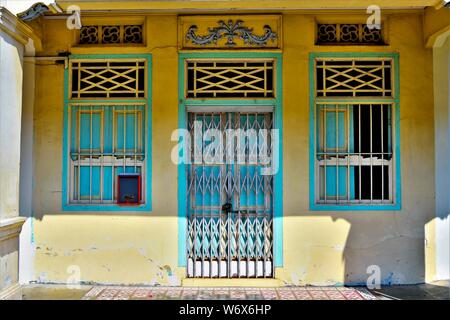 Ingresso al tradizionale negozio Peranakan house con blu e crema porta di antiquariato e windows sulla parete gialla nella storica città di Geylang, Singapore Foto Stock