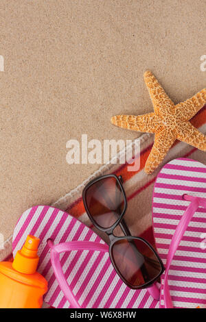 Estate accessori infradito e asciugamano. Spiaggia di sabbia la texture dello sfondo. Con spazio per il design, il testo posto. Foto Stock