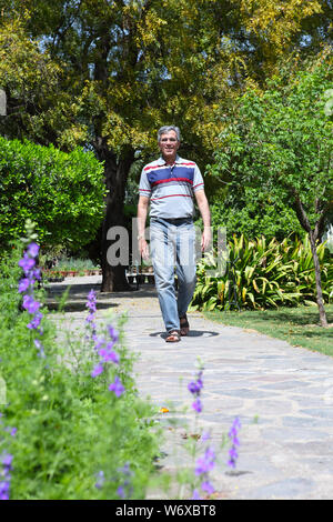 Senior uomo a camminare in un parco Foto Stock