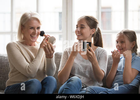 Funny bambina con la madre e nonna di applicare il make up Foto Stock