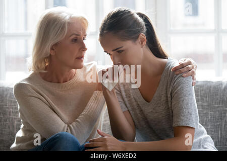 Amorevole Madre di età calmare la figlia adulta famiglia seduta sul lettino Foto Stock