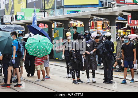 La Causeway Bay DI HONG KONG - Luglio 25, 2019: manifestanti nascondere la loro identità con ombrelloni mentre essi svitare e rimuovere le barriere pedonali in anticipo Foto Stock