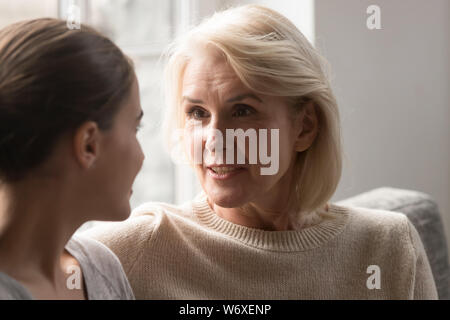 Madre anziana in chat con cresciuti figlia seduta sul lettino Foto Stock