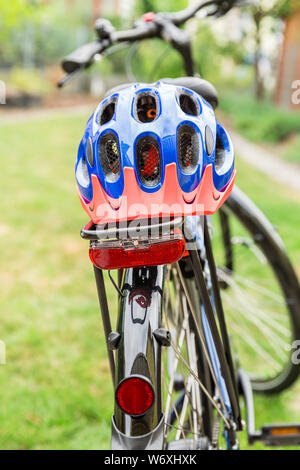 Bicicletta con il casco protettivo disposto sulla cremagliera Foto Stock