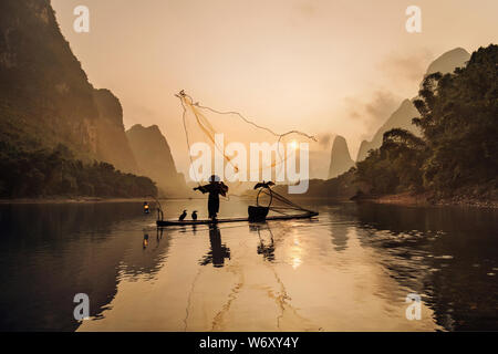 Cormorano tradizionale pescatore, Blackbeard colata di una rete da pesca a sunrise, vicino Xingping, Cina. Foto Stock